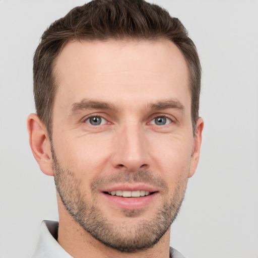 Joyful white young-adult male with short  brown hair and grey eyes