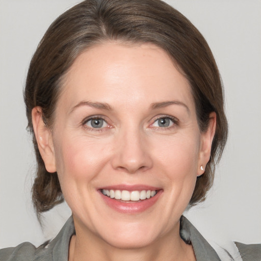 Joyful white adult female with medium  brown hair and grey eyes