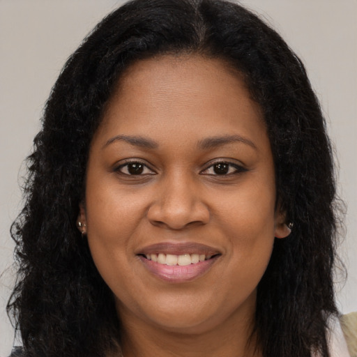 Joyful black young-adult female with long  brown hair and brown eyes