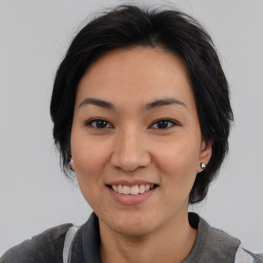 Joyful asian adult female with medium  black hair and brown eyes