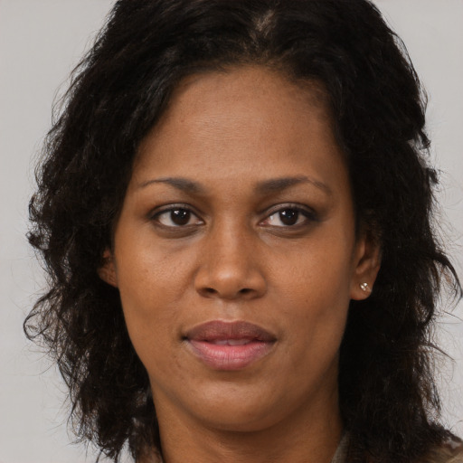 Joyful black adult female with long  brown hair and brown eyes