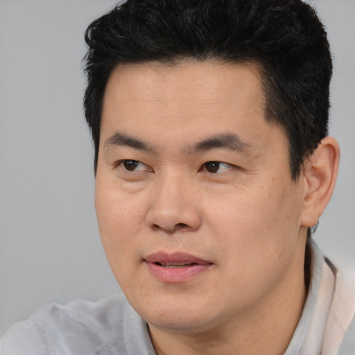 Joyful asian young-adult male with short  brown hair and brown eyes