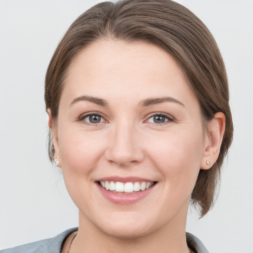 Joyful white young-adult female with medium  brown hair and grey eyes