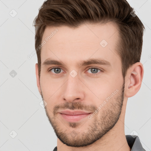 Joyful white young-adult male with short  brown hair and grey eyes