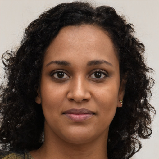 Joyful black young-adult female with long  brown hair and brown eyes