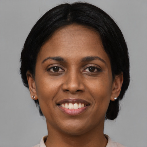 Joyful black young-adult female with short  black hair and brown eyes