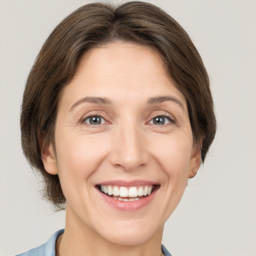 Joyful white adult female with medium  brown hair and grey eyes