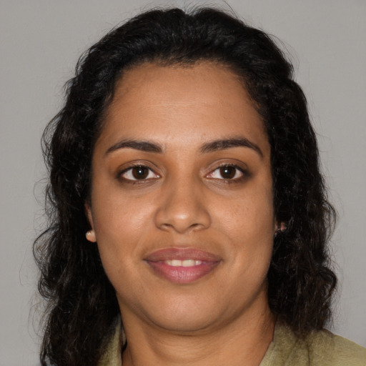 Joyful black young-adult female with long  brown hair and brown eyes