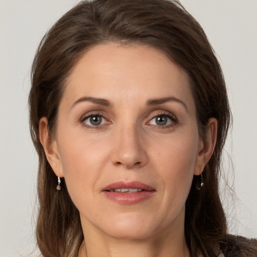 Joyful white adult female with long  brown hair and grey eyes