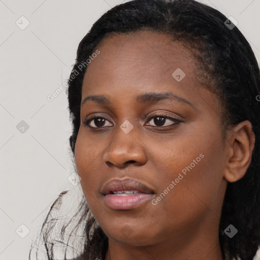 Joyful black young-adult female with long  black hair and brown eyes