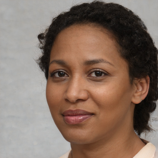 Joyful black adult female with medium  brown hair and brown eyes