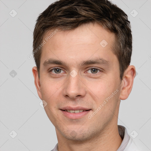 Joyful white young-adult male with short  brown hair and grey eyes