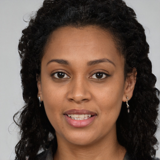 Joyful black young-adult female with long  brown hair and brown eyes