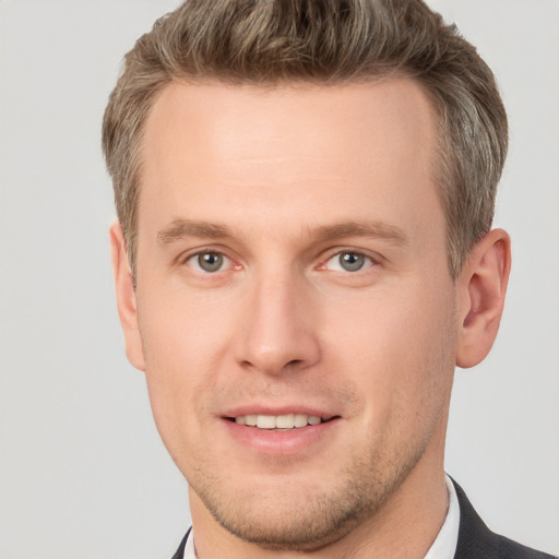 Joyful white young-adult male with short  brown hair and grey eyes