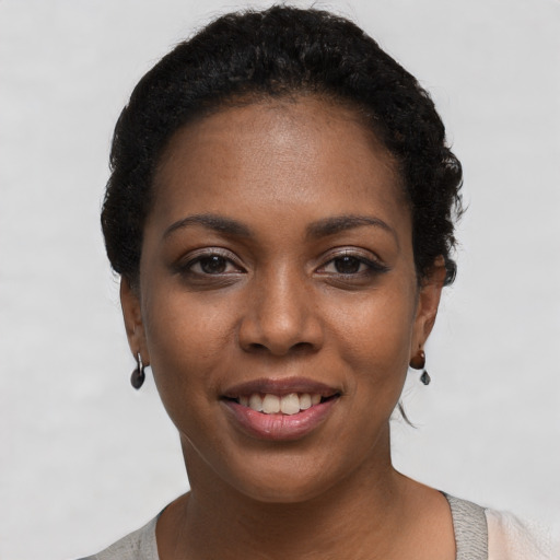 Joyful black young-adult female with short  black hair and brown eyes
