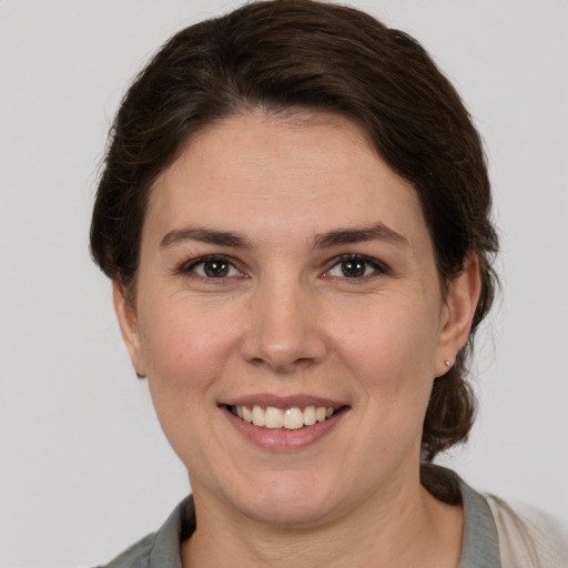 Joyful white young-adult female with medium  brown hair and grey eyes