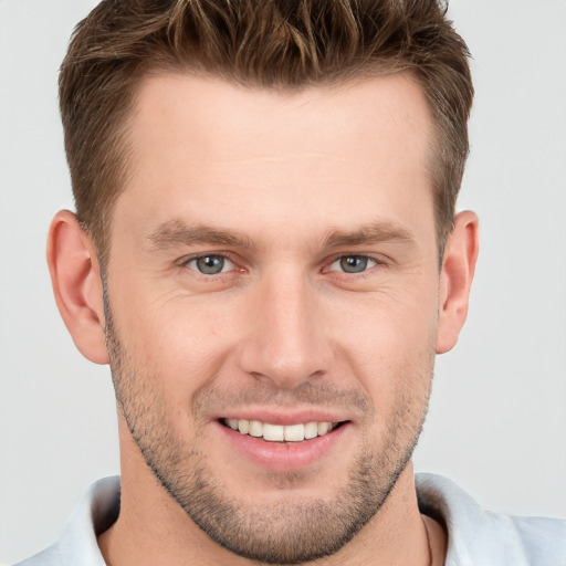 Joyful white young-adult male with short  brown hair and grey eyes