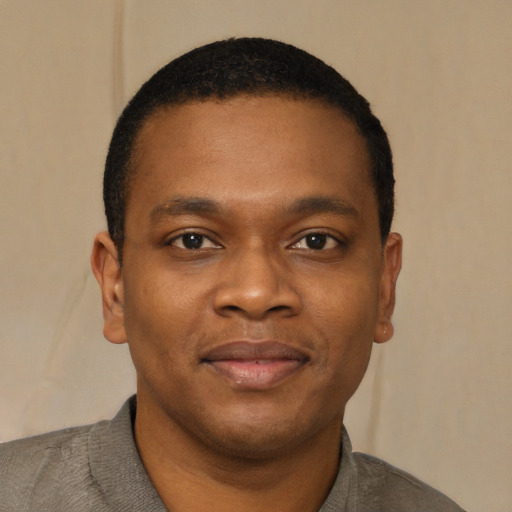Joyful black young-adult male with short  brown hair and brown eyes