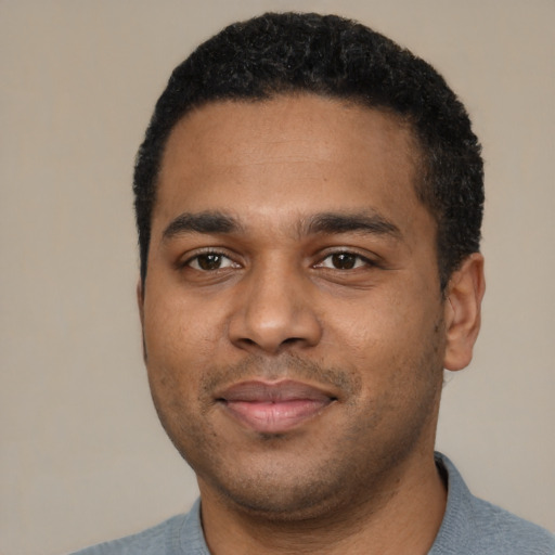 Joyful black young-adult male with short  black hair and brown eyes