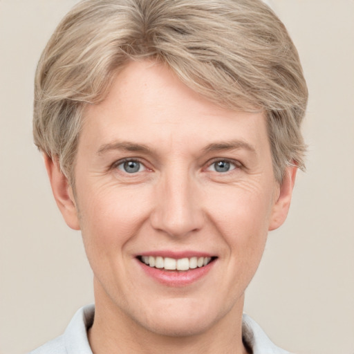 Joyful white adult female with short  blond hair and grey eyes