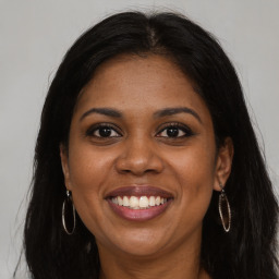 Joyful black young-adult female with long  brown hair and brown eyes