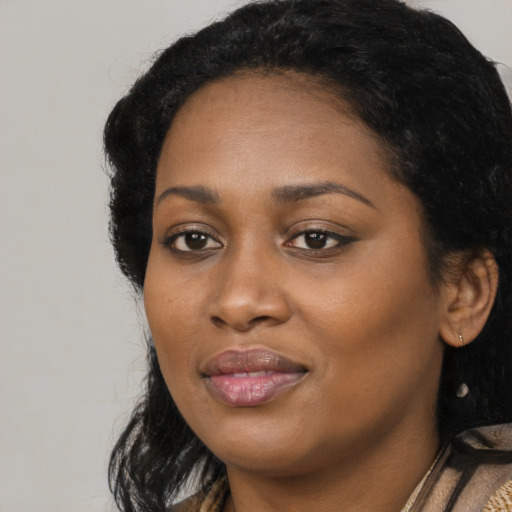 Joyful black young-adult female with long  black hair and brown eyes