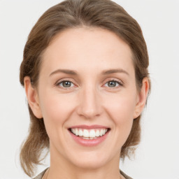 Joyful white young-adult female with medium  brown hair and grey eyes