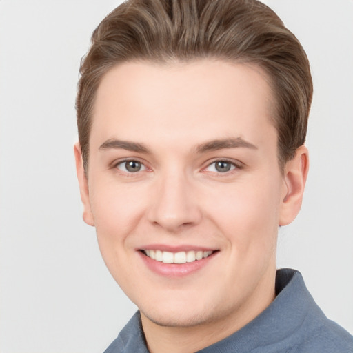 Joyful white young-adult male with short  brown hair and grey eyes