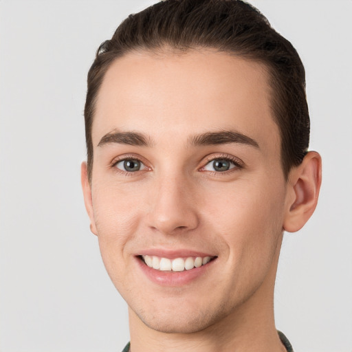 Joyful white young-adult male with short  brown hair and grey eyes