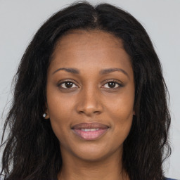 Joyful black young-adult female with long  brown hair and brown eyes