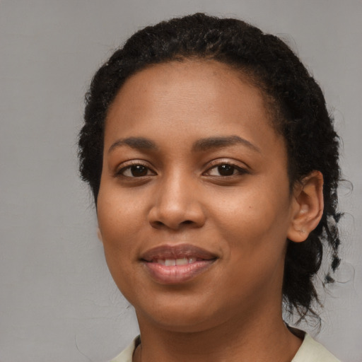 Joyful black young-adult female with long  brown hair and brown eyes