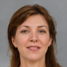 Joyful white adult female with long  brown hair and grey eyes