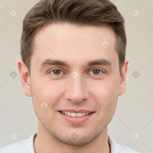 Joyful white young-adult male with short  brown hair and grey eyes