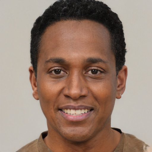 Joyful black young-adult male with short  black hair and brown eyes