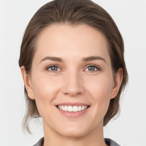 Joyful white young-adult female with medium  brown hair and grey eyes