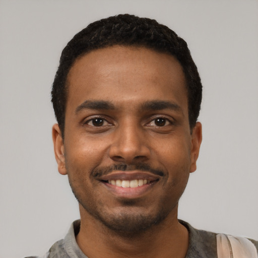Joyful black young-adult male with short  black hair and brown eyes