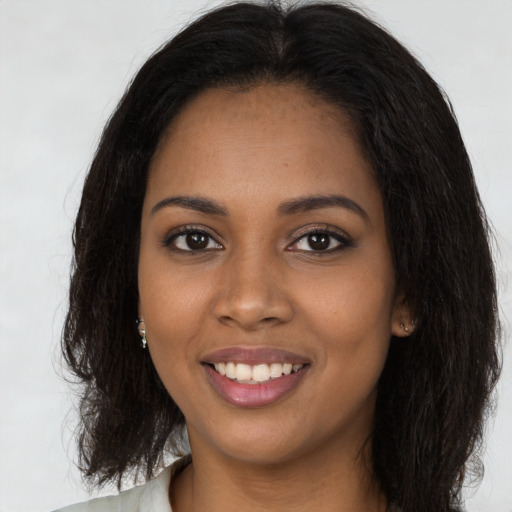 Joyful black young-adult female with long  brown hair and brown eyes