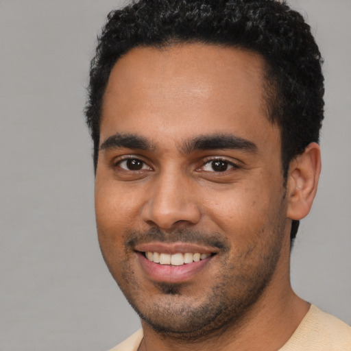 Joyful black young-adult male with short  brown hair and brown eyes