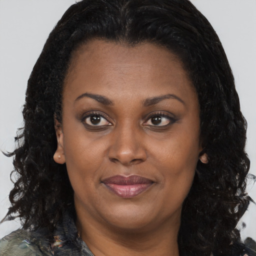 Joyful black adult female with long  brown hair and brown eyes