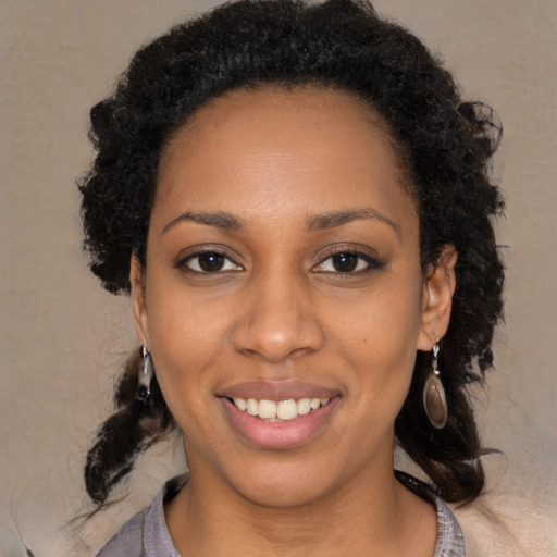 Joyful black young-adult female with long  black hair and brown eyes