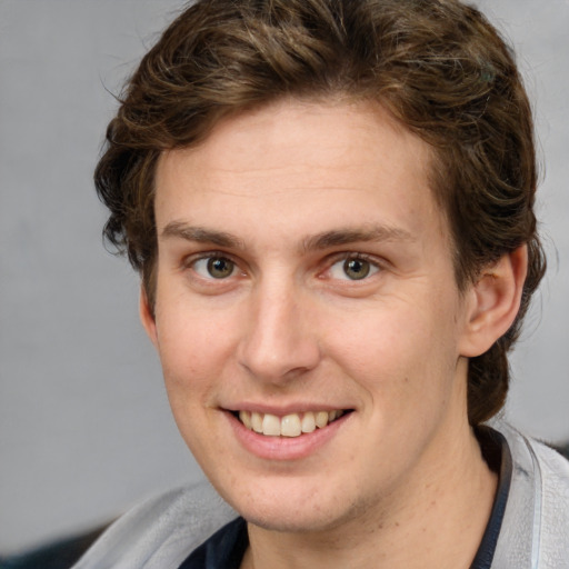 Joyful white young-adult male with medium  brown hair and grey eyes