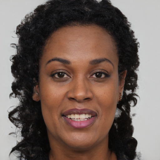 Joyful black adult female with long  brown hair and brown eyes