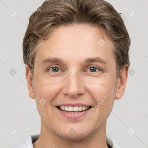 Joyful white young-adult male with short  brown hair and grey eyes