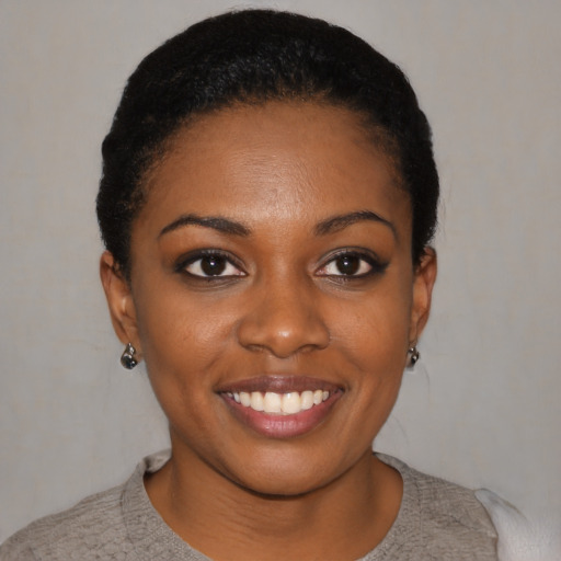 Joyful black young-adult female with short  black hair and brown eyes
