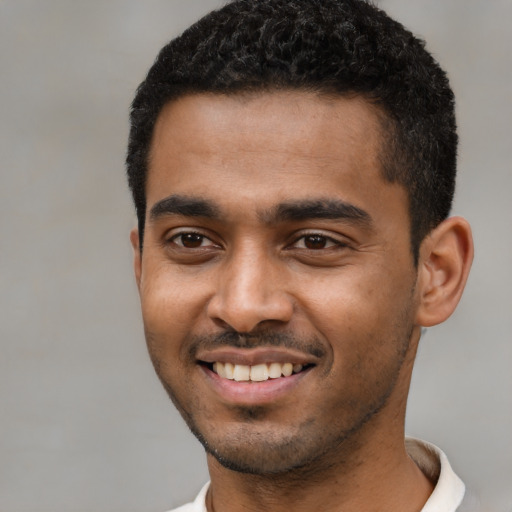 Joyful black young-adult male with short  black hair and brown eyes