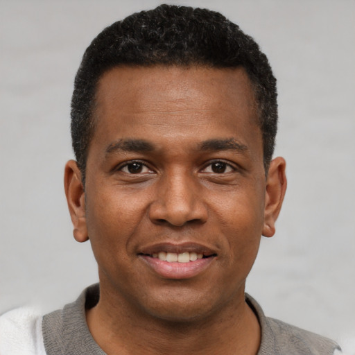 Joyful black young-adult male with short  black hair and brown eyes