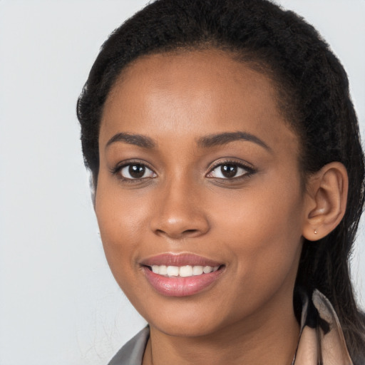 Joyful black young-adult female with long  black hair and brown eyes