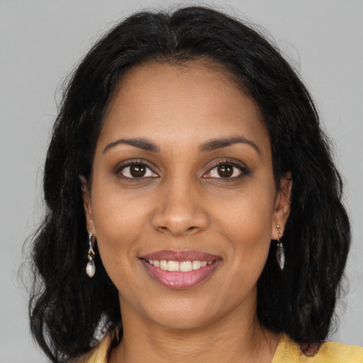 Joyful black young-adult female with long  brown hair and brown eyes