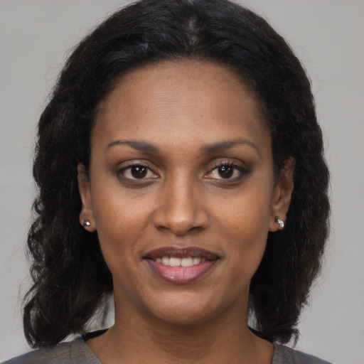 Joyful black adult female with long  brown hair and brown eyes