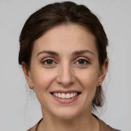 Joyful white young-adult female with medium  brown hair and grey eyes